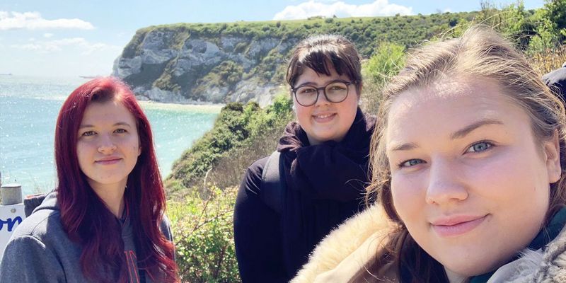 drei junge Mitarbeiterinnen machen ein Selfie im Hintergrund Klippen und das Meer 